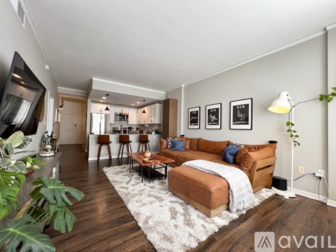 A living room with a brown couch and a white rug.