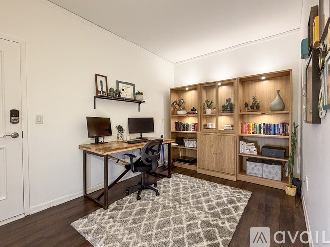 A room with a desk, chair, and shelves with various items.
