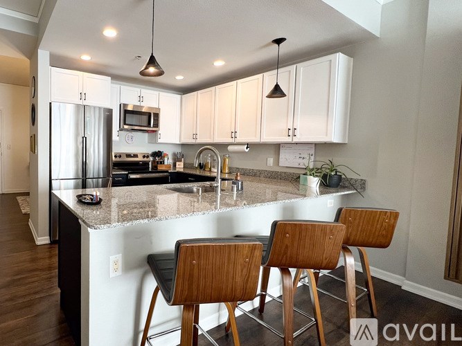 A kitchen with a granite countertop and wooden bar stools.
