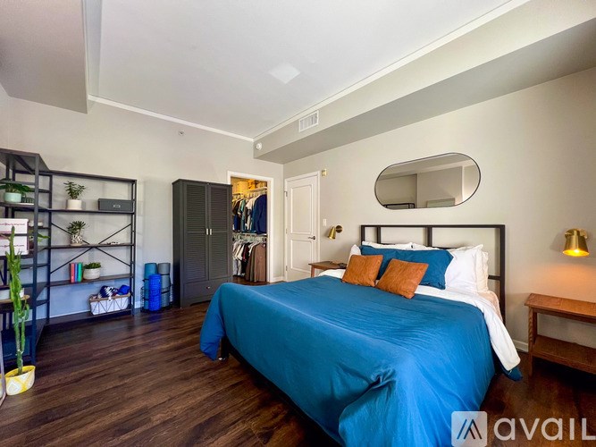 A bedroom with a blue bedspread and a mirror above it.