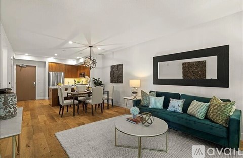 A living room with a green couch and a dining table with chairs.