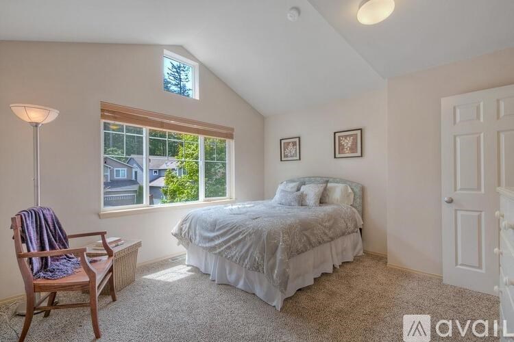A bedroom with a bed, chair, and window.
