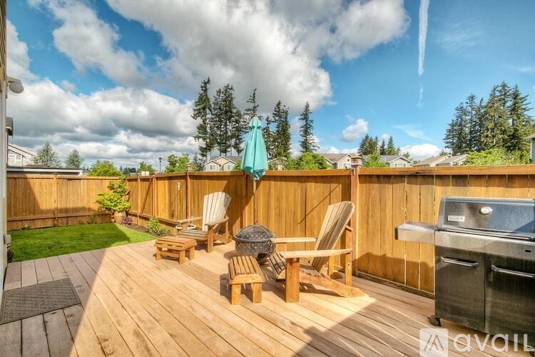 A wooden deck with chairs and a grill.