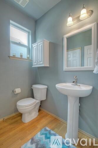 A bathroom with a toilet, sink, and mirror.