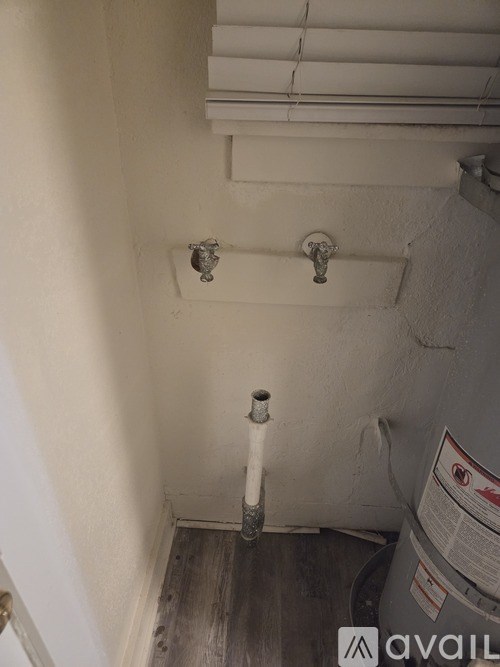 A white pipe runs down the center of a wall.