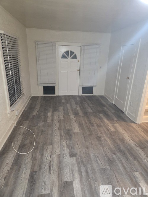A room with wooden flooring and white walls.