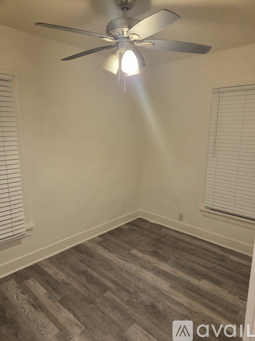 A room with a ceiling fan and wooden flooring.