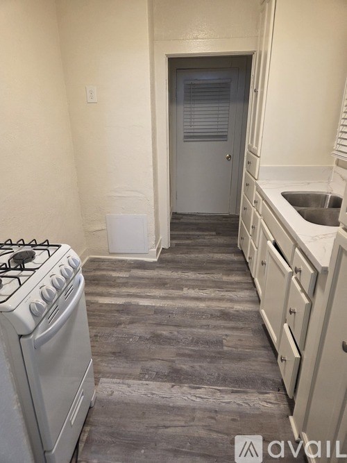 A kitchen with a white stove and cabinets.