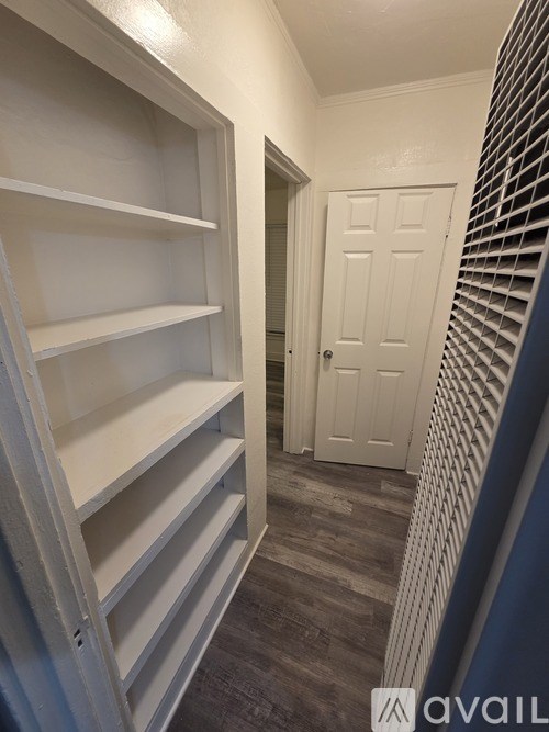 Empty shelves in a hallway leading to a door.