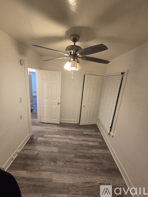 A room with a ceiling fan and two doors.