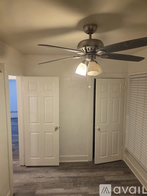 A room with a ceiling fan and two doors.