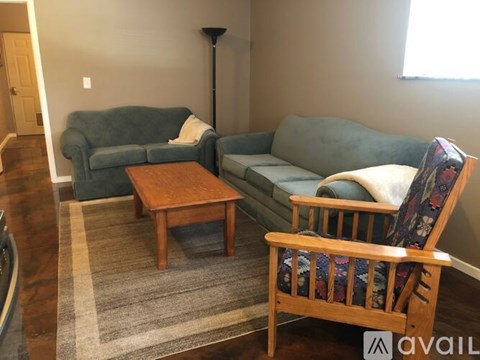 A living room with a blue couch, a wooden coffee table, and a wooden chair with a colorful cushion.