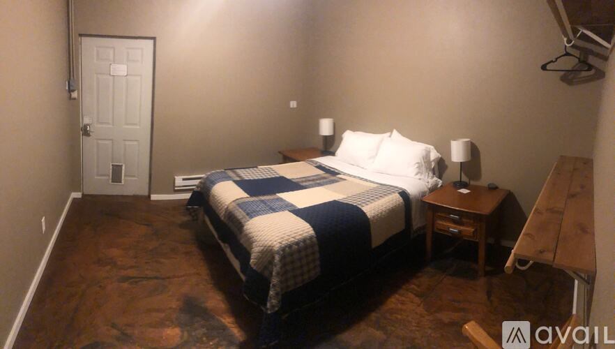 A bedroom with a bed, nightstand, and lamp.