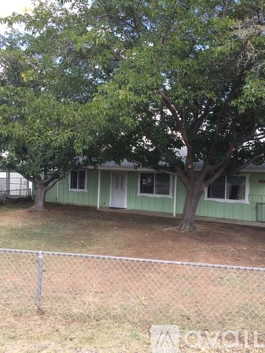 A green house with a tree in front of it.