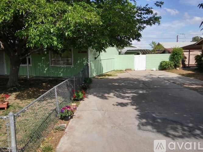 A green house with a fence and a tree in front.