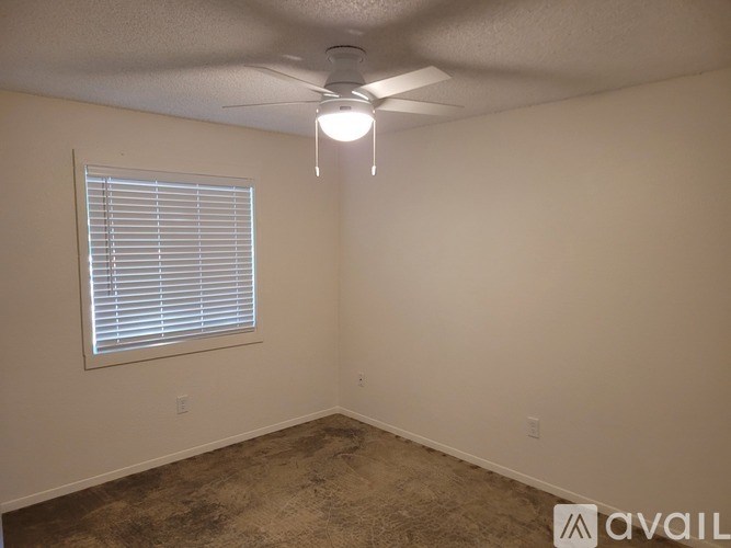 A room with a ceiling fan and a window with blinds.