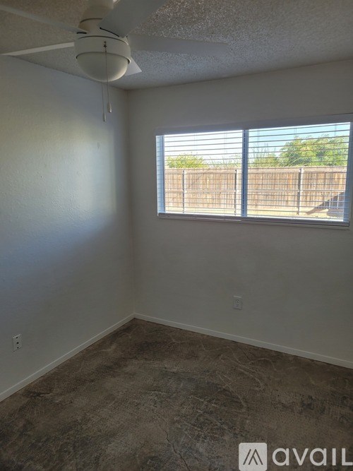 A room with a window and a fan on the ceiling.