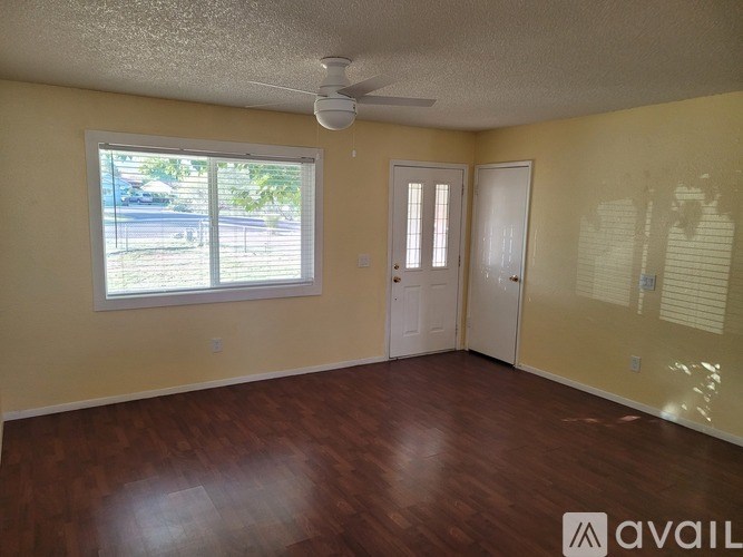 A room with a window, two doors, and a ceiling fan.