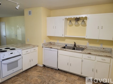A kitchen with a white stove top oven and white cabinets.