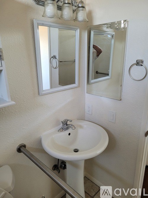 A bathroom with a white sink and mirrors.