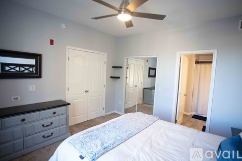 A bedroom with a bed, dresser, and ceiling fan.