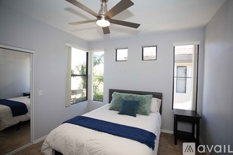 A bedroom with a bed, a ceiling fan, and a window.
