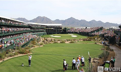 A golfer is preparing to hit a ball on a golf course with a mountain in the background.