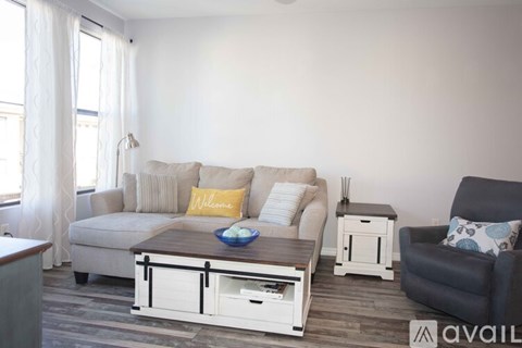 A living room with a grey couch, a coffee table, and a black armchair.