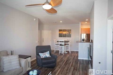 A living room with a grey couch, a black chair, and a wooden floor.