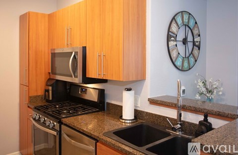 A kitchen with wooden cabinets and a clock on the wall.