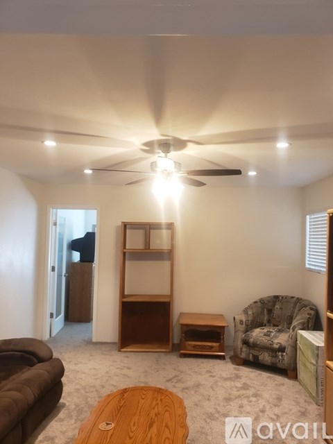 A living room with a brown couch, a wooden coffee table, and a ceiling fan.