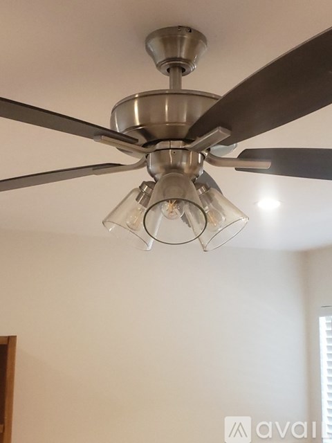 A silver ceiling fan with a light bulb in the middle.