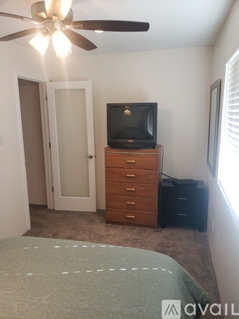 A bedroom with a bed, dresser, and a television.