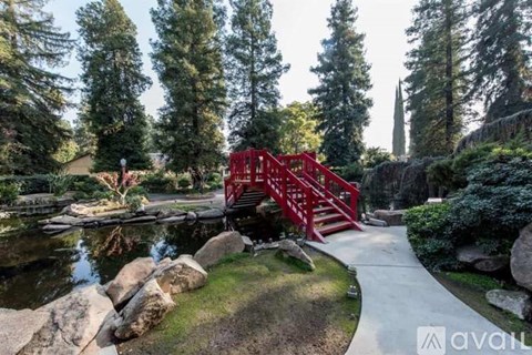 A red bridge over a pond in a lush green garden.