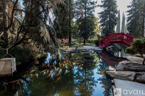 A red bridge over a body of water surrounded by trees.
