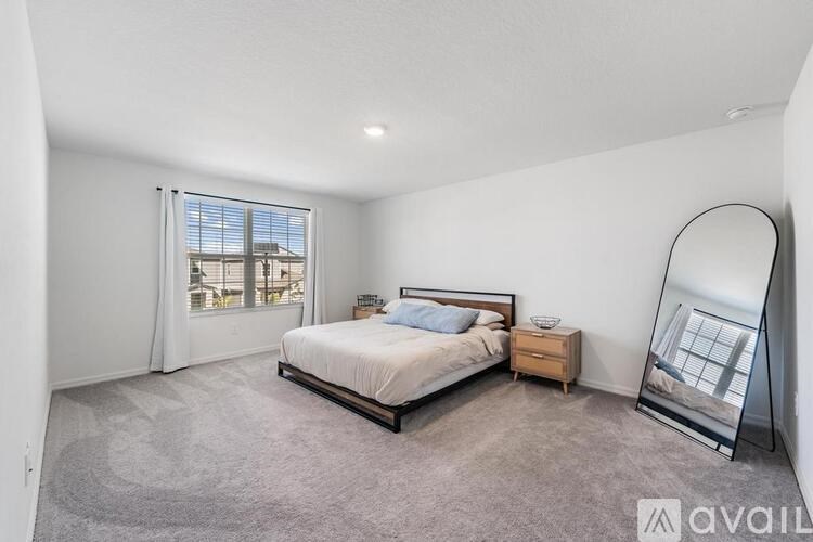 A bedroom with a large bed, a nightstand, and a window with a view of the city.