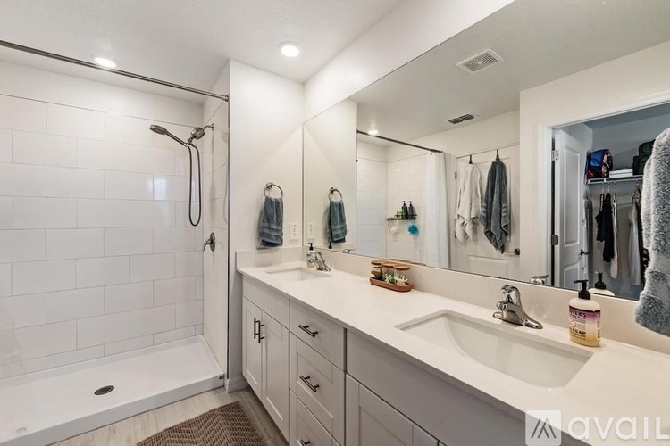 A bathroom with a white tiled shower and a white sink.