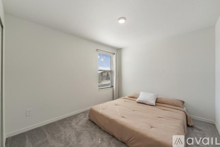 A bedroom with a bed, pillows, and a window with blinds.