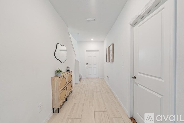 A hallway with a wooden floor and white walls.