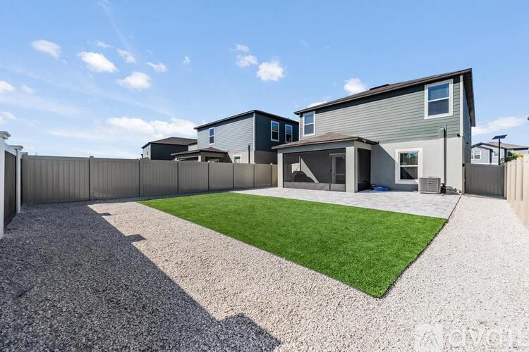 A modern house with a grey roof and a gravel driveway.