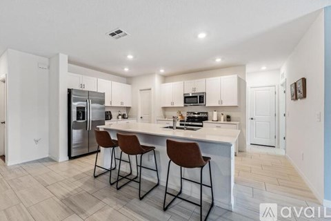 A kitchen with white cabinets and a center island with two chairs.