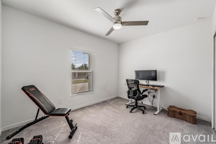 A room with a chair, a desk, and a ceiling fan.