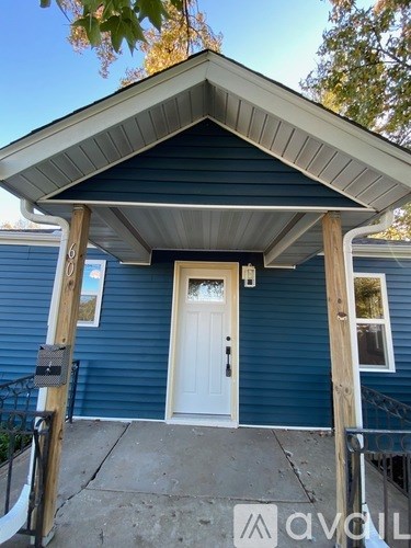A small blue house with a white door and a small porch.