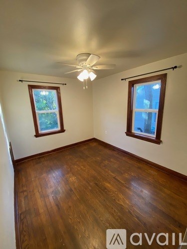 A room with wooden floors and two windows.