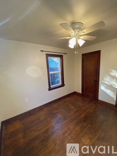 A room with a ceiling fan and wooden floors.