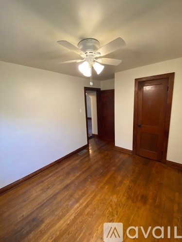 A room with a ceiling fan and wooden floors.