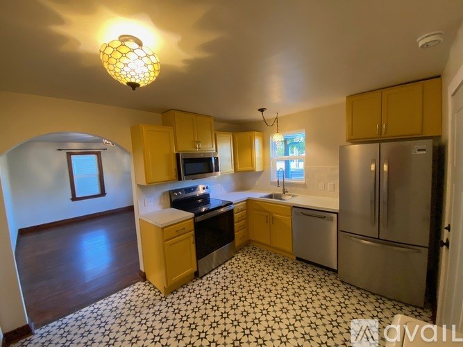 A kitchen with yellow cabinets and a black and white floor.