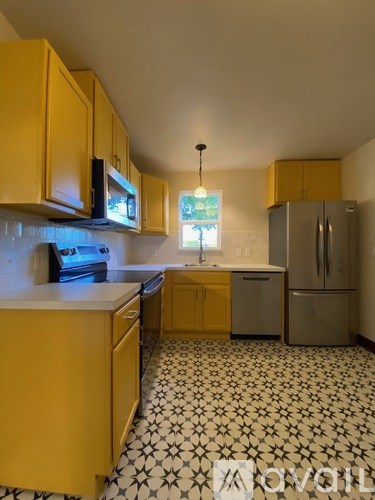 A kitchen with yellow cabinets and a black and white floor.