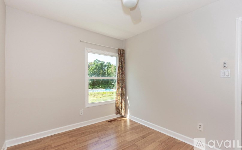 A room with a window and a fan on the ceiling.