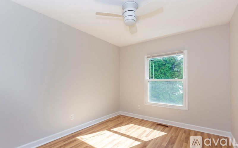 A room with a window and a fan on the ceiling.